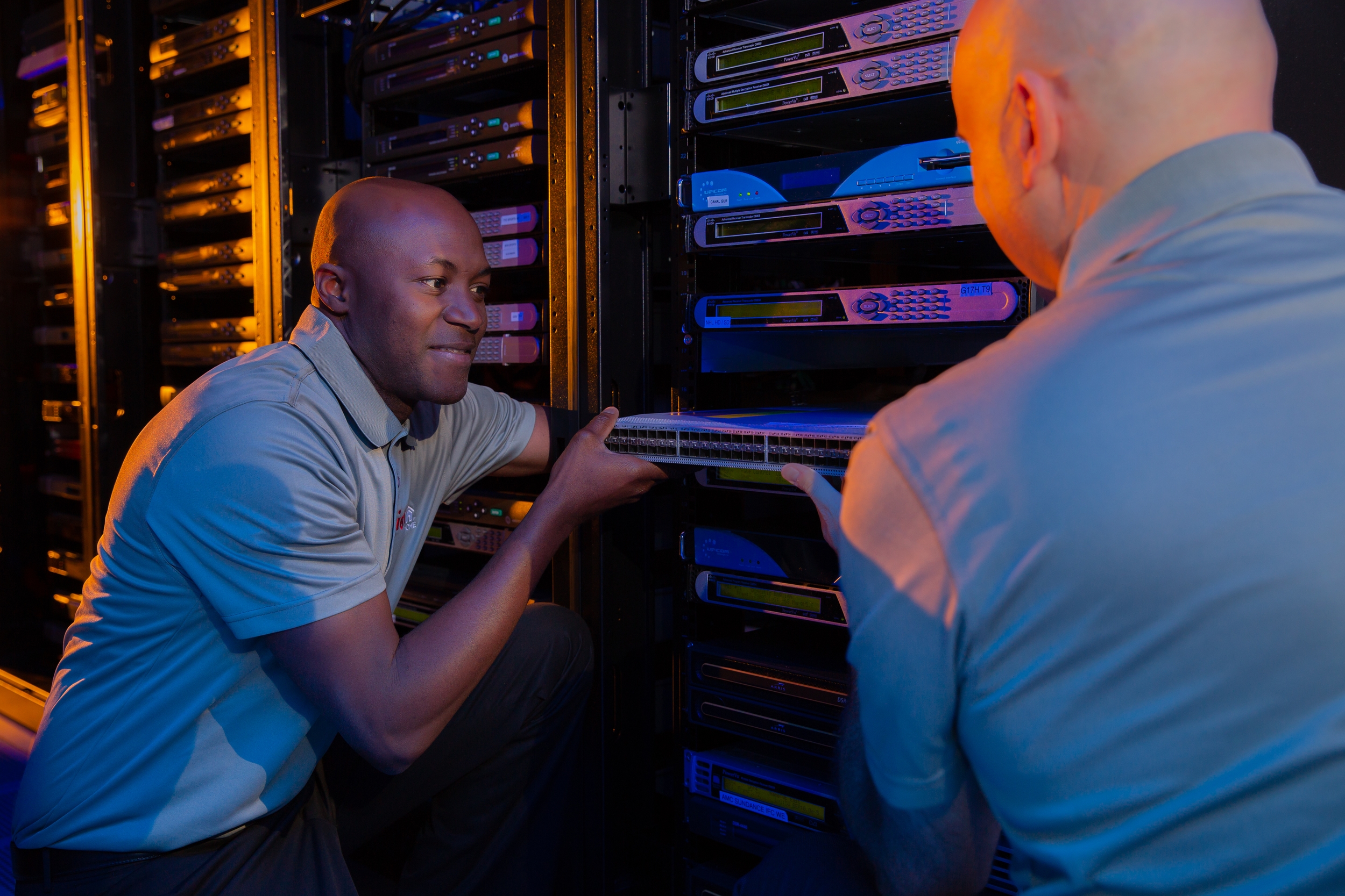 Two men work together to adjust part of a server system.