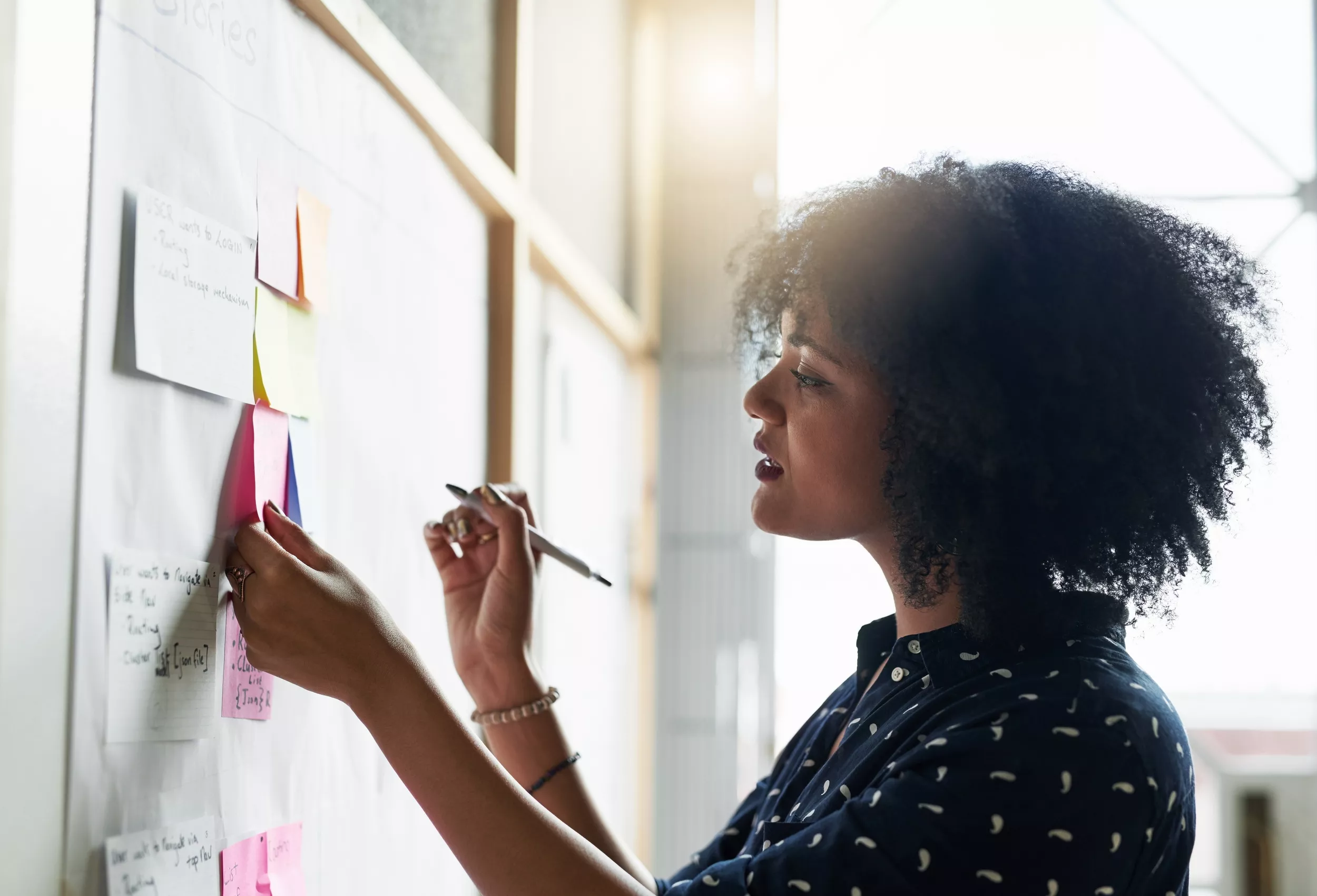 Woman works on a note against a whiteboard.